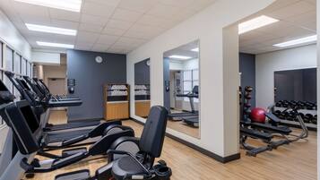 A gym with treadmills, exercise bikes, and free weights.