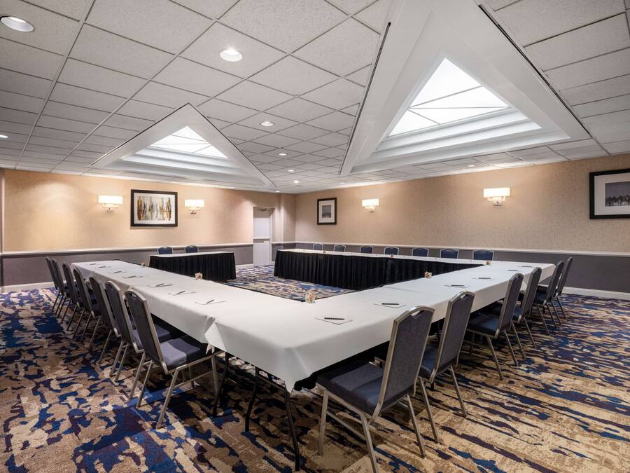 Une salle de conférence avec une longue table, des chaises et un tapis à motifs.