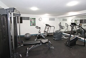 Een sportschool met diverse fitnessapparaten, waaronder een loopband, elliptische trainer en gewichtstoestellen.