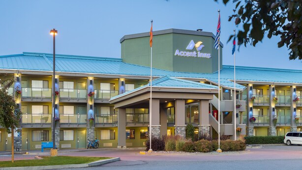 A multi-story hotel with a green roof, balconies with flower boxes, and a sign reading "Accent Inns". - Accent Inns Kamloops (Kamloops)