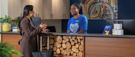 A reception desk with a wooden log display, a laptop, and a coffee machine.