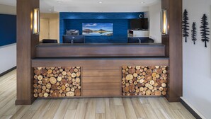 A reception area with a wooden reception desk, a large framed landscape painting, and a wall-mounted television.