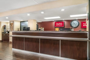 A hotel reception desk with a clock, a red sign indicating free Wi-Fi, and a wall-mounted clock.