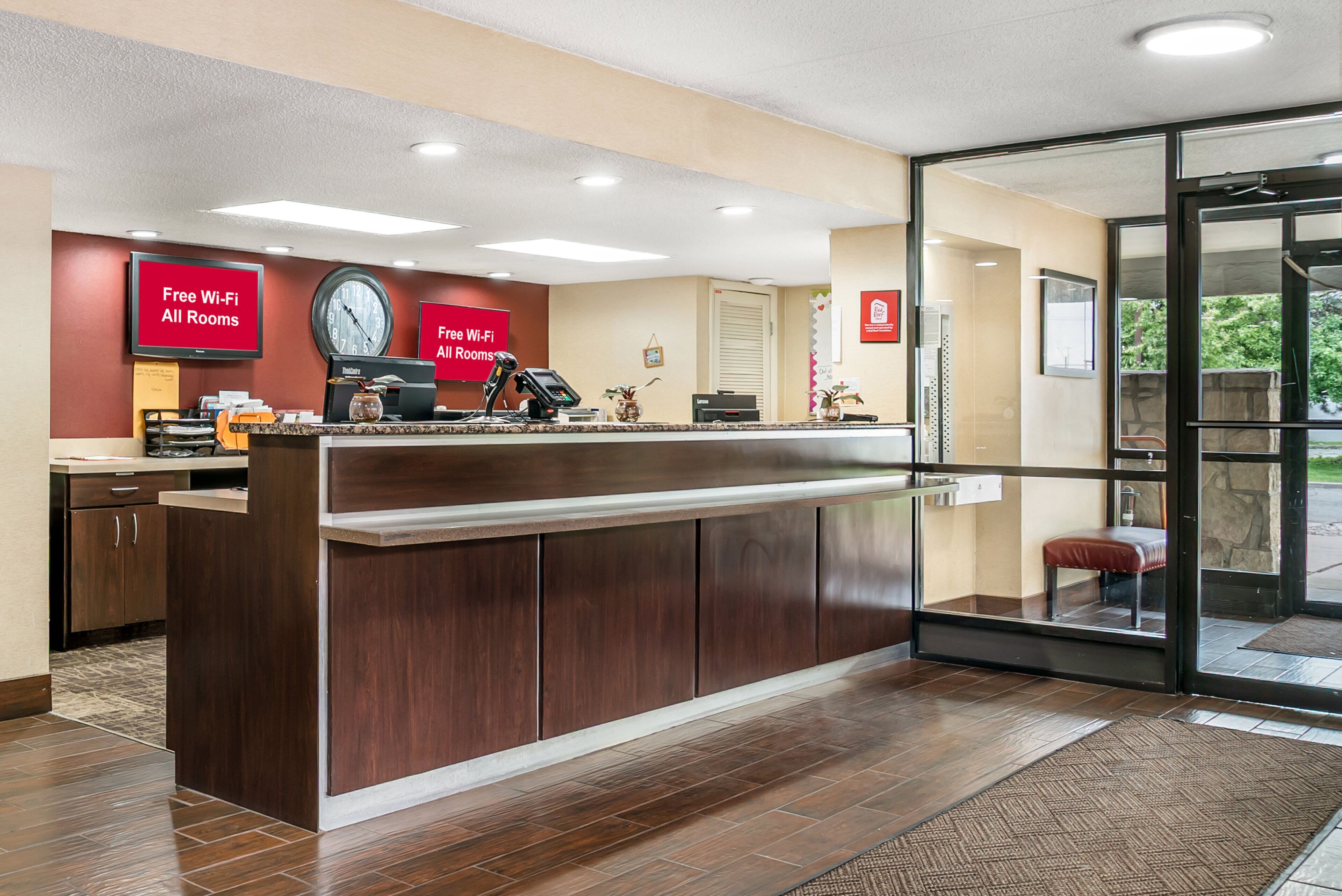A reception desk with a clock, a digital display, and a sign indicating free Wi-Fi in all rooms.