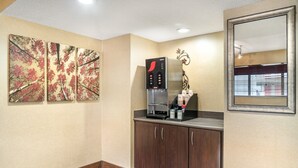 A hotel room with a coffee machine, a mirror, and artwork on the wall. - Red Roof Inn Detroit Metro Airport - Taylor (Taylor)