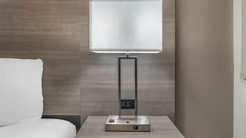 Ein modernes Hotelzimmer mit Nachttisch, Flachbildfernseher und Bedienfeld.