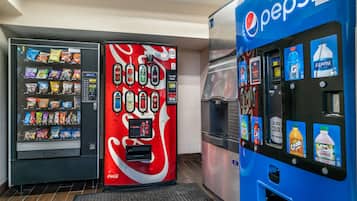 Uma área de máquinas de venda automática com máquinas Coca-Cola, Pepsi e um bebedouro.