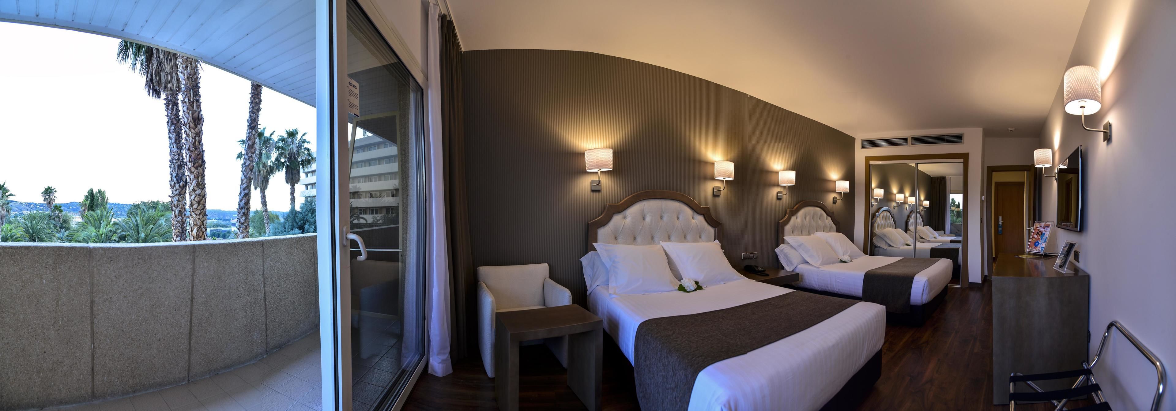 Una habitación de hotel con una cama grande, un área de descanso y vistas a palmeras.