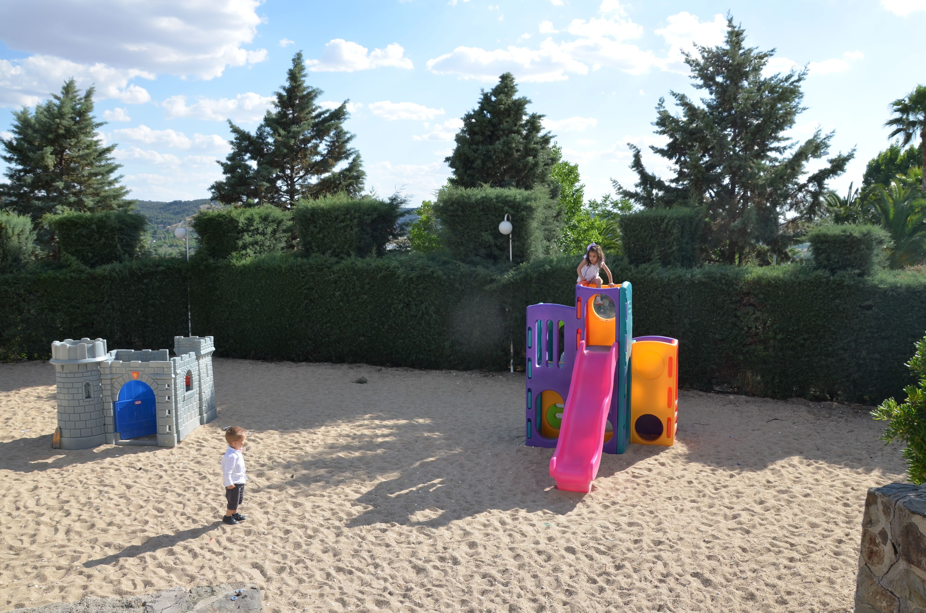 A sandy play area with a castle and colorful play structures.