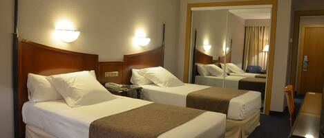 Habitación de hotel con dos camas, un escritorio y un espejo.