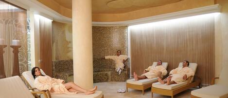 A spa area with lounge chairs, a large pillar, and a mosaic wall.
