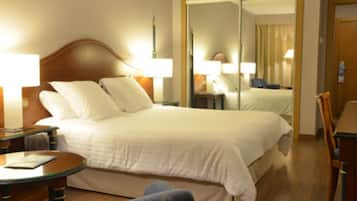 A hotel room with a bed, bedside tables, a chair, and a mirror.