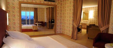 Une chambre d’hôtel avec un lit, un bureau, une chaise et une salle de bain que l’on peut voir à travers un miroir.