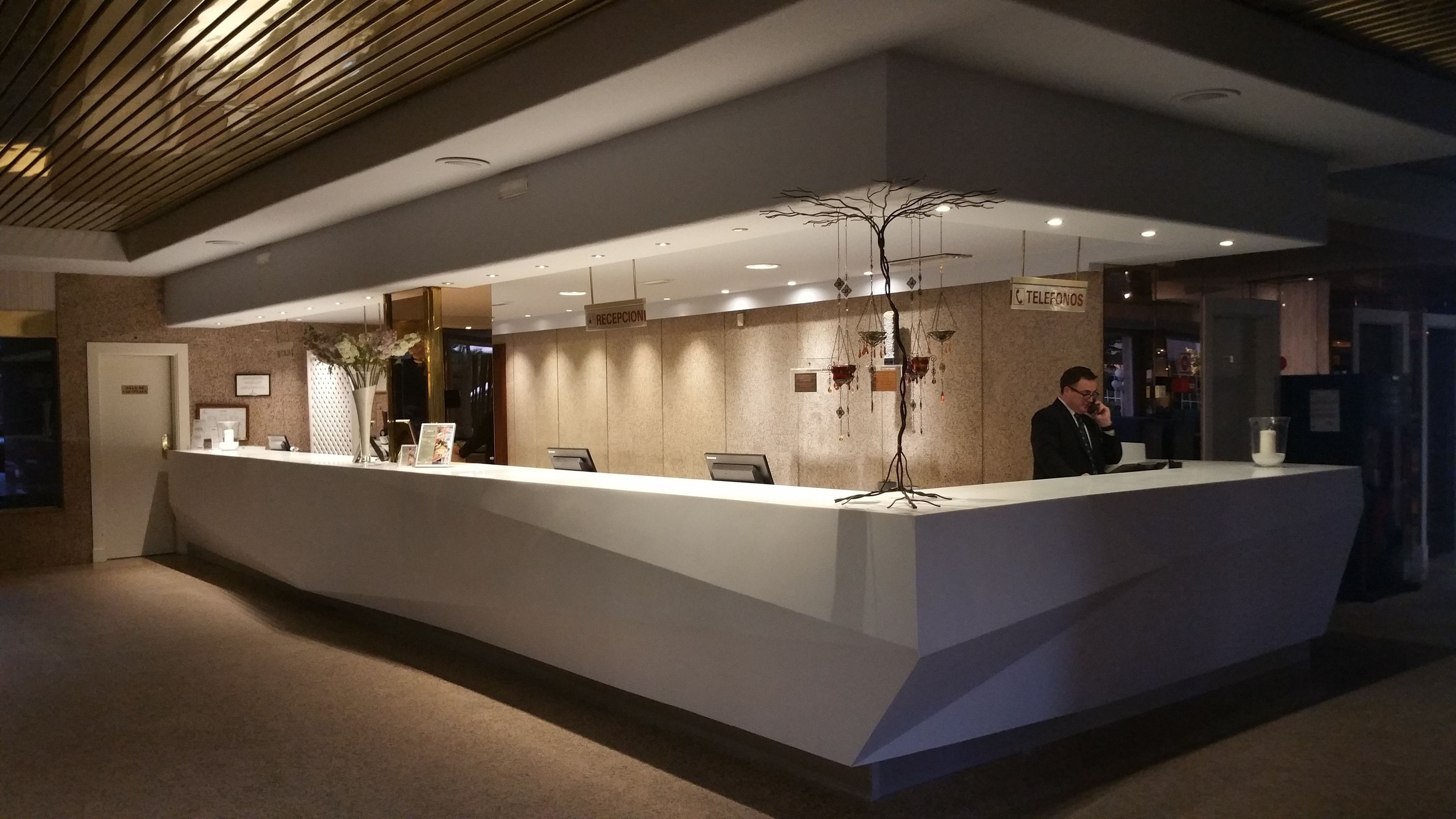 A reception desk with a modern design, a sign indicating the reception area, and a decorative tree-like structure above it.
