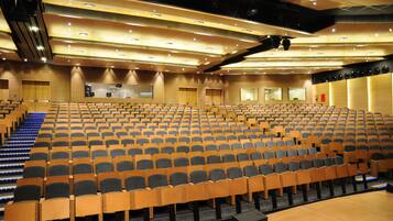 Een auditorium met rijen houten stoelen en een podium.