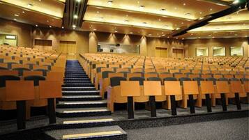 Un amplio auditorio con asientos escalonados, un escenario central y un diseño moderno.