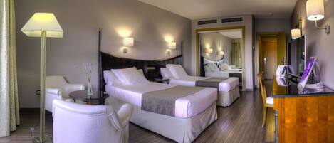 A hotel room with two beds, a desk, a chair, a lamp, and a mirror.