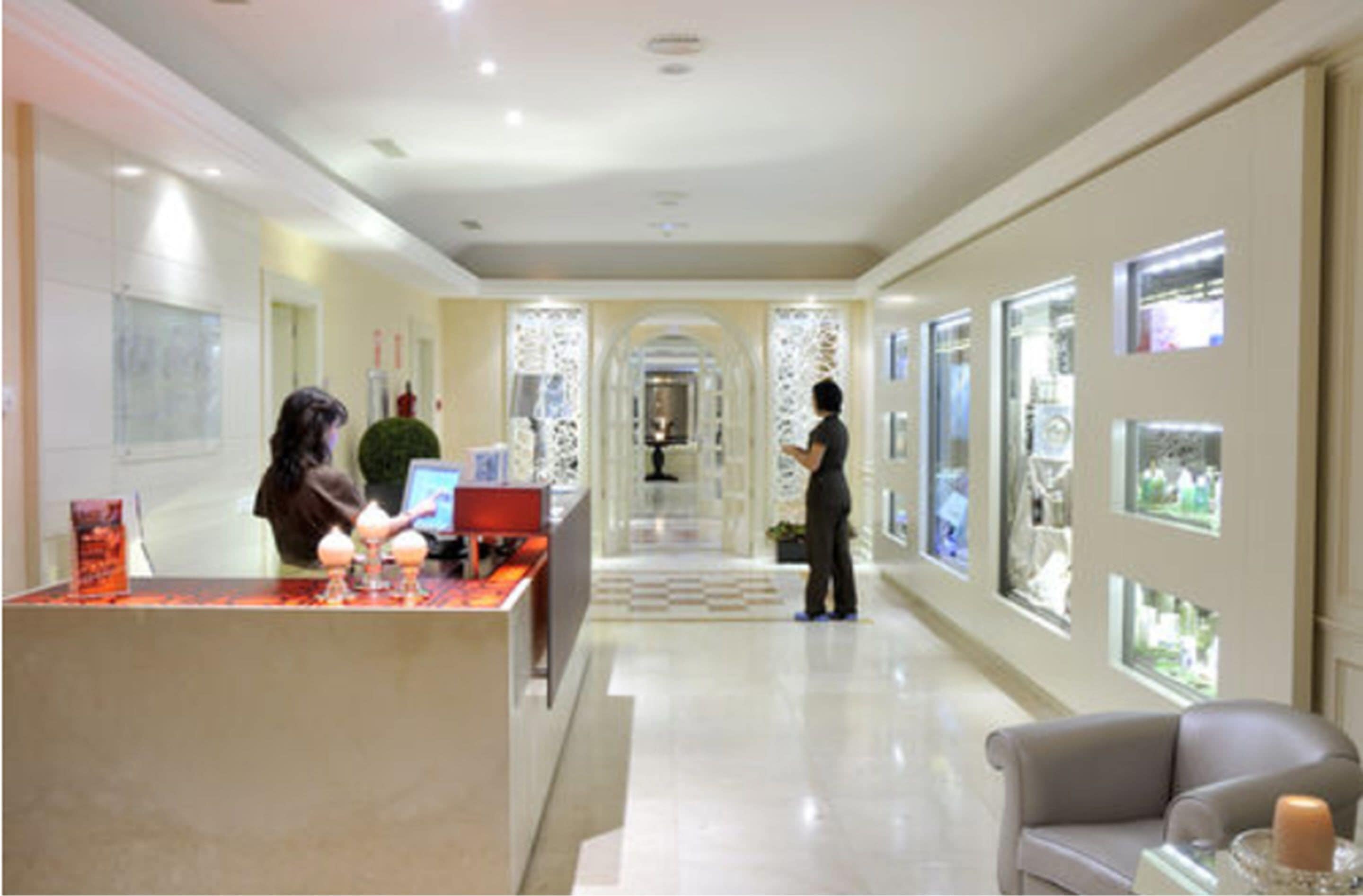 A hotel lobby with a reception desk, a seating area, and a decorative wall with framed pictures.