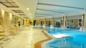 A large indoor swimming pool with multiple lanes, lounge chairs, and a statue. - Hotel Beatriz Toledo Auditorium & Spa (Toledo)