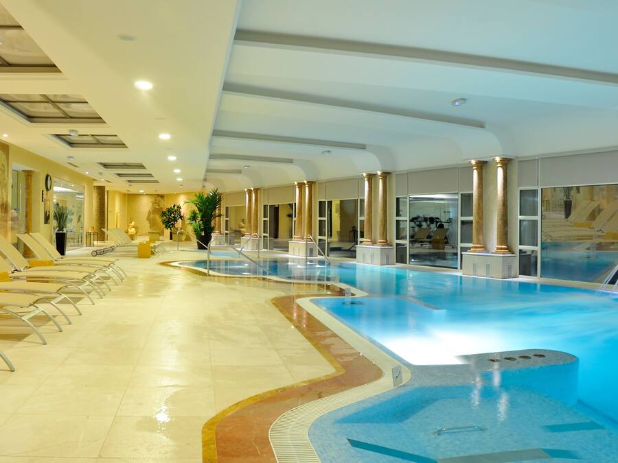 A large indoor swimming pool with multiple lanes, lounge chairs, and a statue.