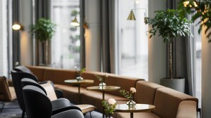 A modern lounge area with sofas, round tables, and potted plants. - Radisson Blu Royal Hotel Helsinki (Helsinki)