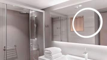 A modern bathroom with a glass-enclosed shower, a white sink, and a large mirror with a circular light.