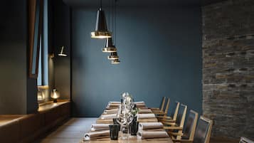 Un comedor con una larga mesa de madera, varias sillas y lámparas colgantes.