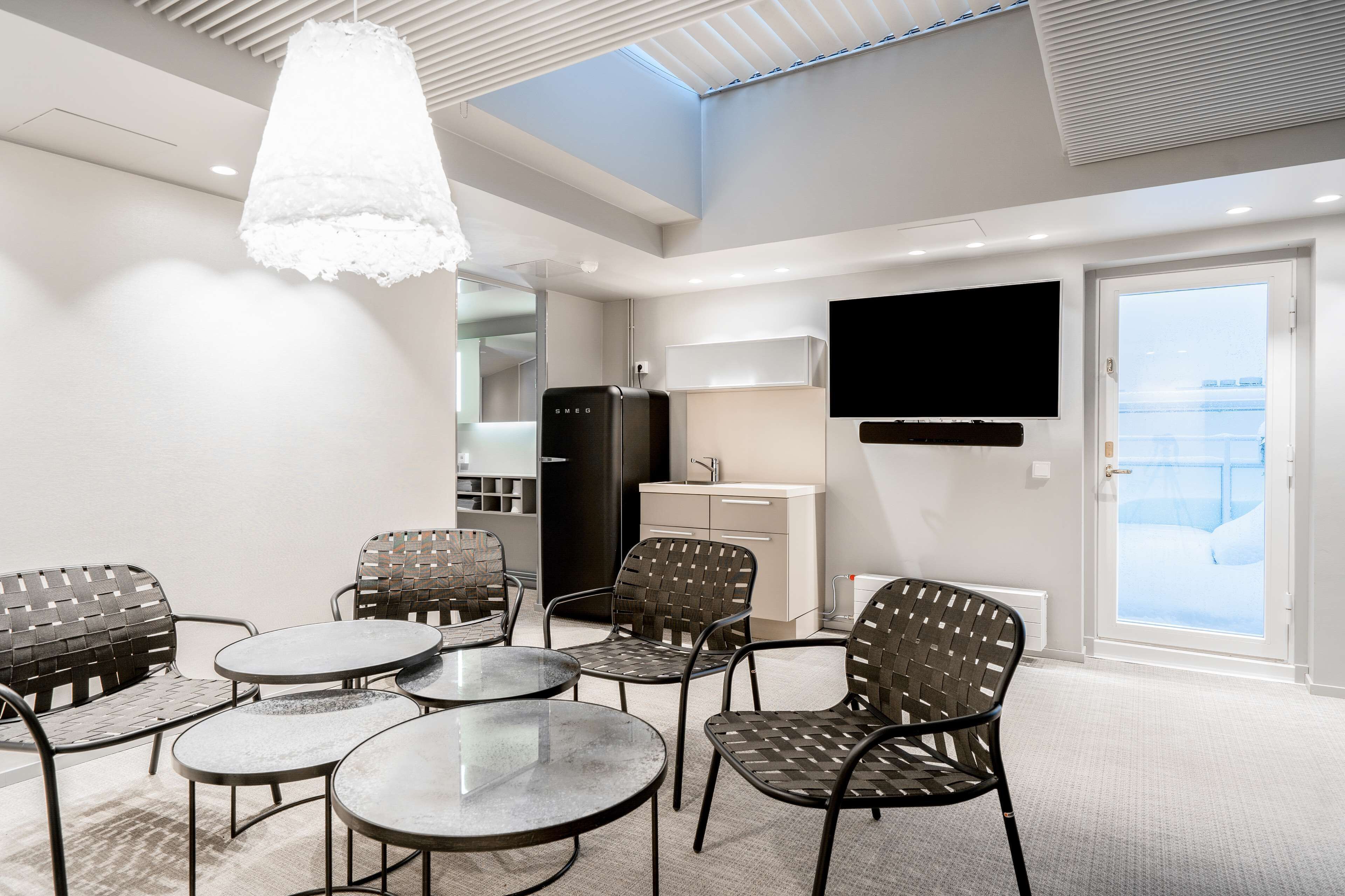 A modern room with a dining area, a flat-screen TV, and a kitchenette.