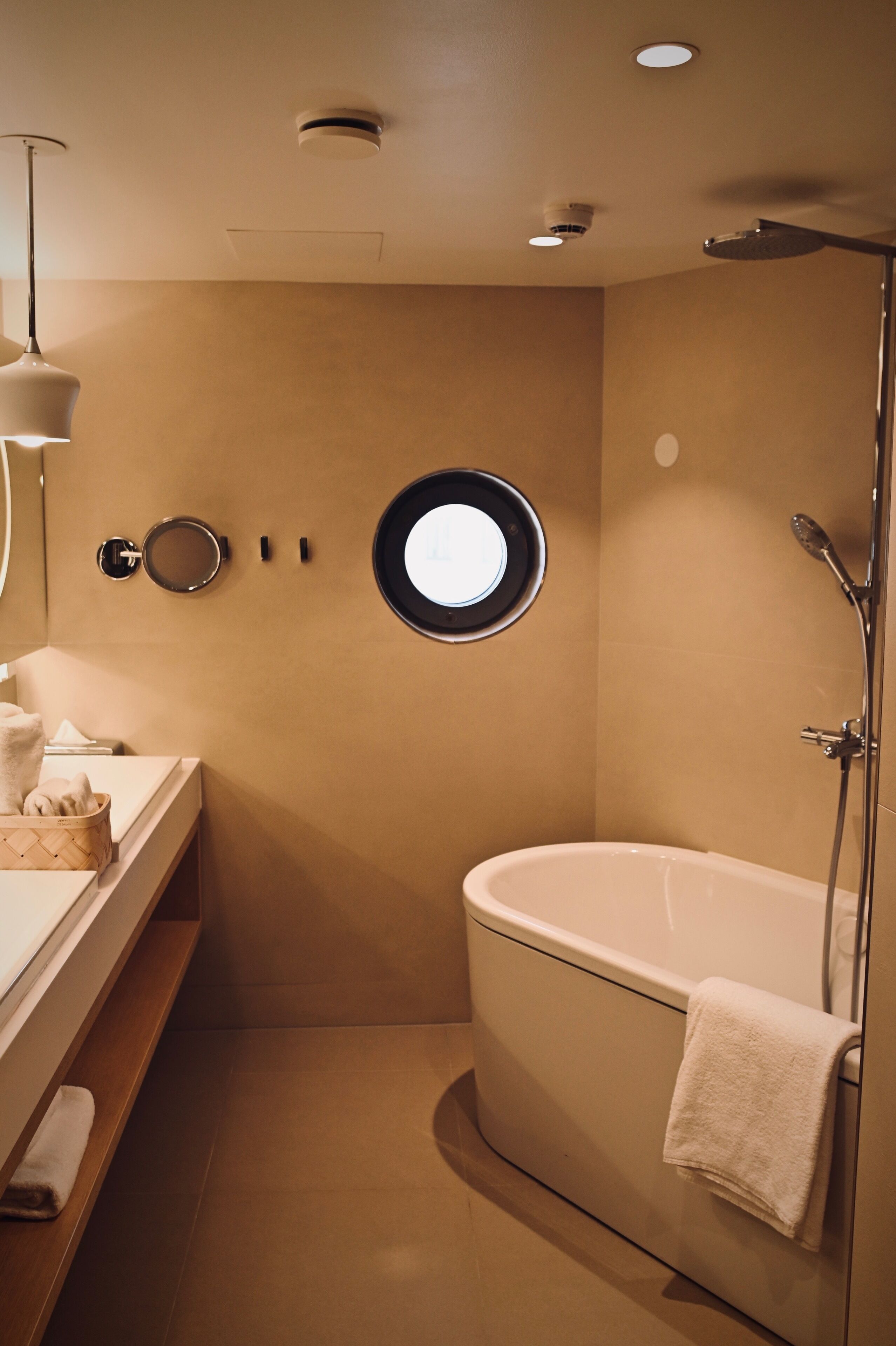 Un baño moderno con una bañera independiente, un espejo redondo y un perchero para toallas.