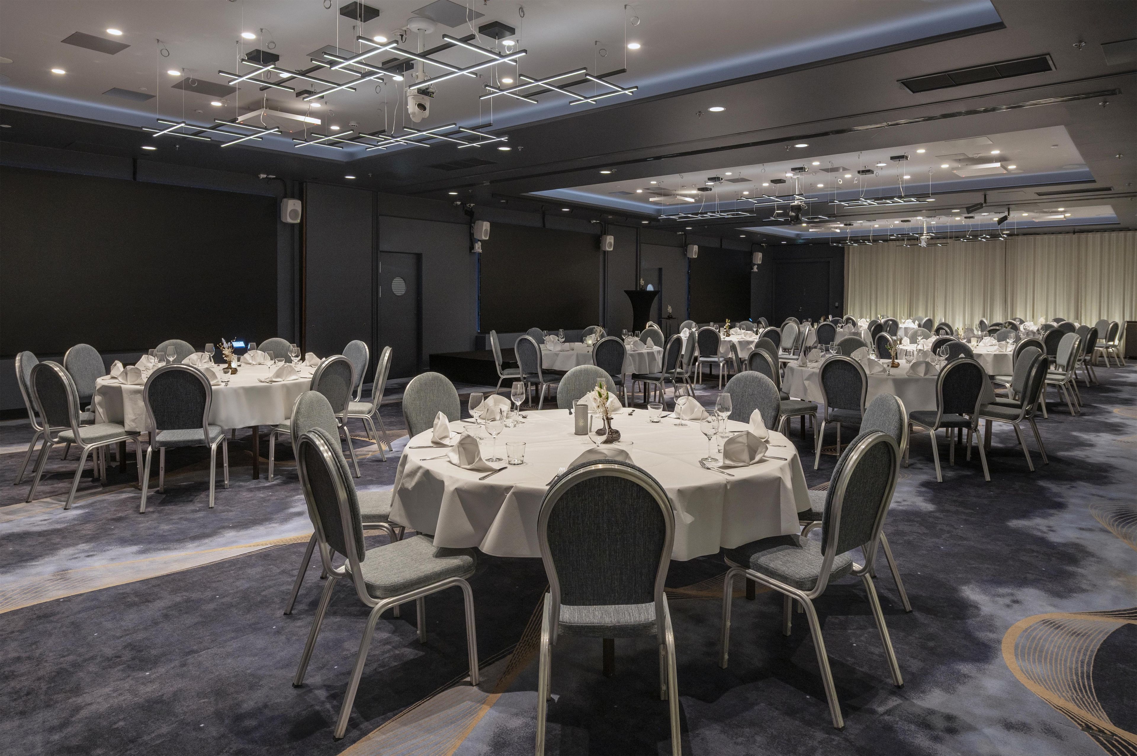 Uma sala de conferências com mesas redondas, cadeiras e um palco com um púlpito.