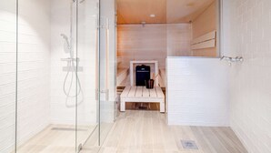 A modern bathroom with a glass shower enclosure, a wooden bench, and a towel rack. - Radisson Blu Royal Hotel Helsinki (Helsinki)