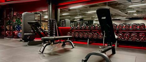 A gym with weightlifting equipment and a mirrored wall.