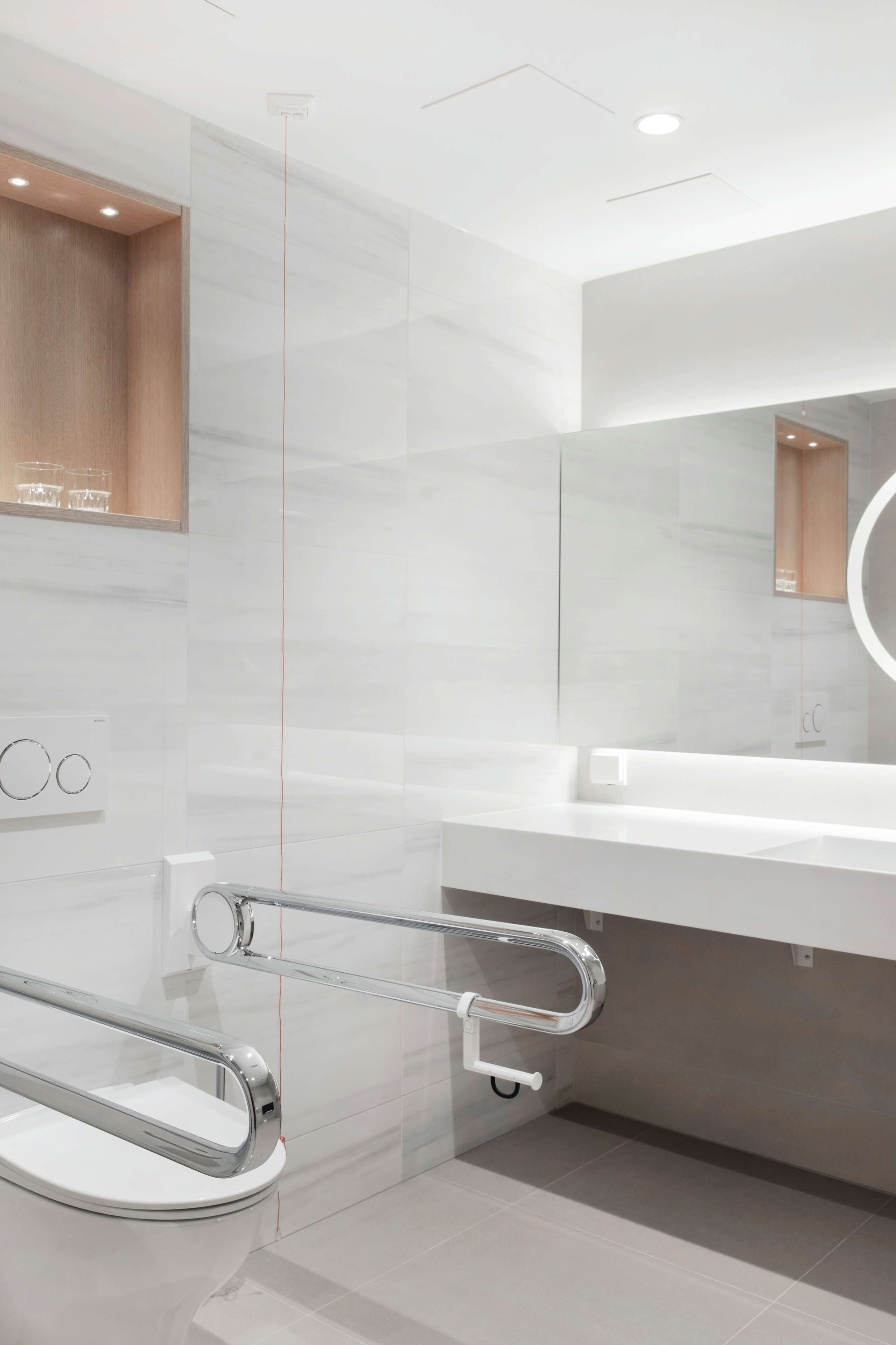 Ein modernes Badezimmer mit einer Glasdusche, einem weißen Waschbecken und einem Spiegel.