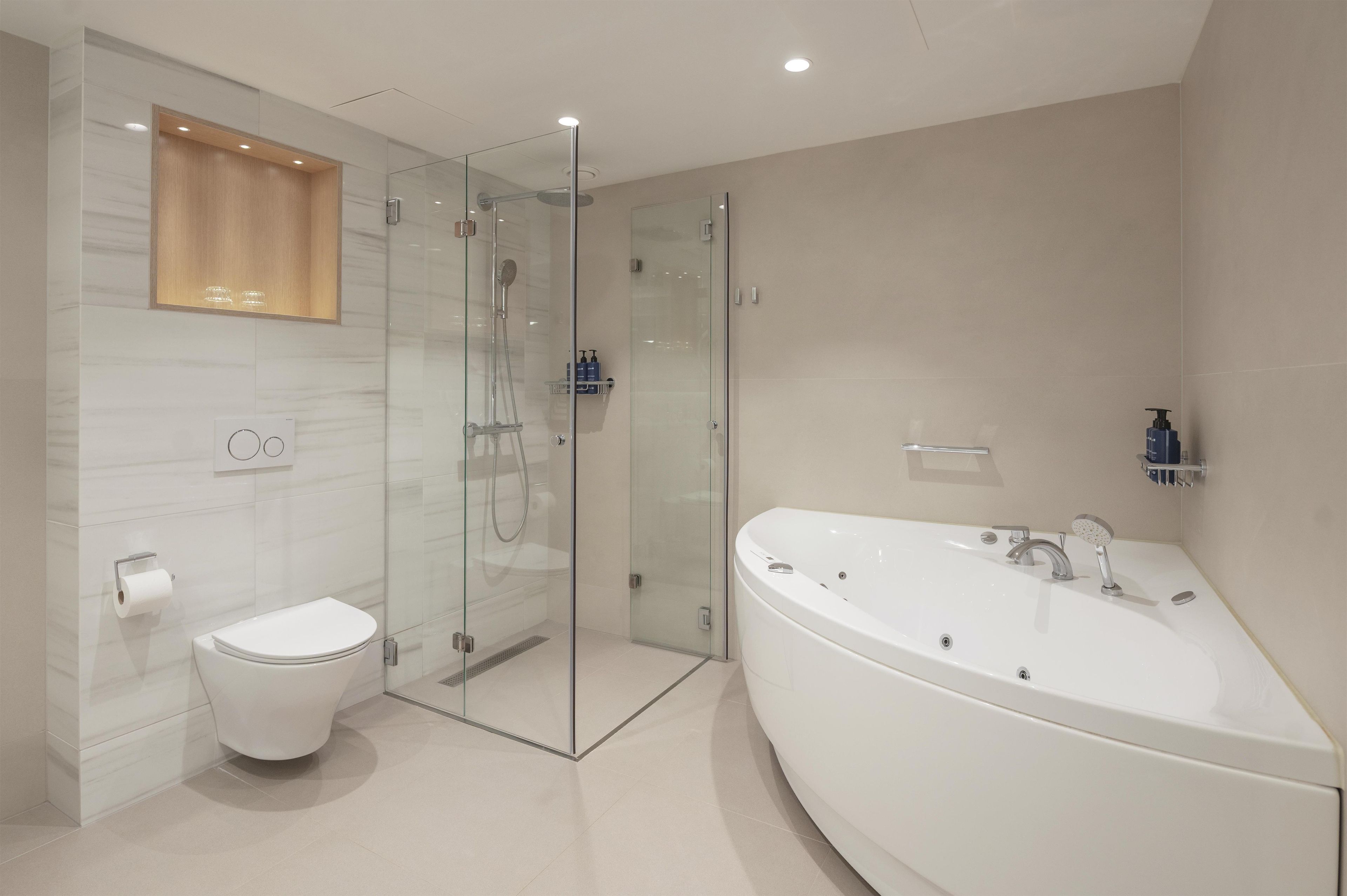 A modern bathroom with a glass-enclosed shower, a white toilet, and a freestanding bathtub.