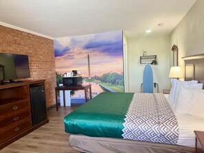 Une chambre d’hôtel avec un lit, une télévision, un bureau avec un ordinateur et une vue sur un parc.