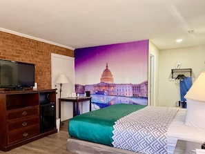 A hotel room with a bed, a TV, a desk, and a mural of a capitol building. - Governor House Inn (Falls Church)