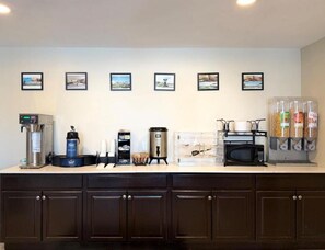 Un espace cuisine équipé d’une machine à café, d’un distributeur de café, d’un four à micro-ondes et d’un distributeur de nourriture.