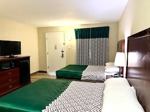Une chambre d’hôtel avec deux lits, une télévision, un bureau avec un ordinateur et une porte.