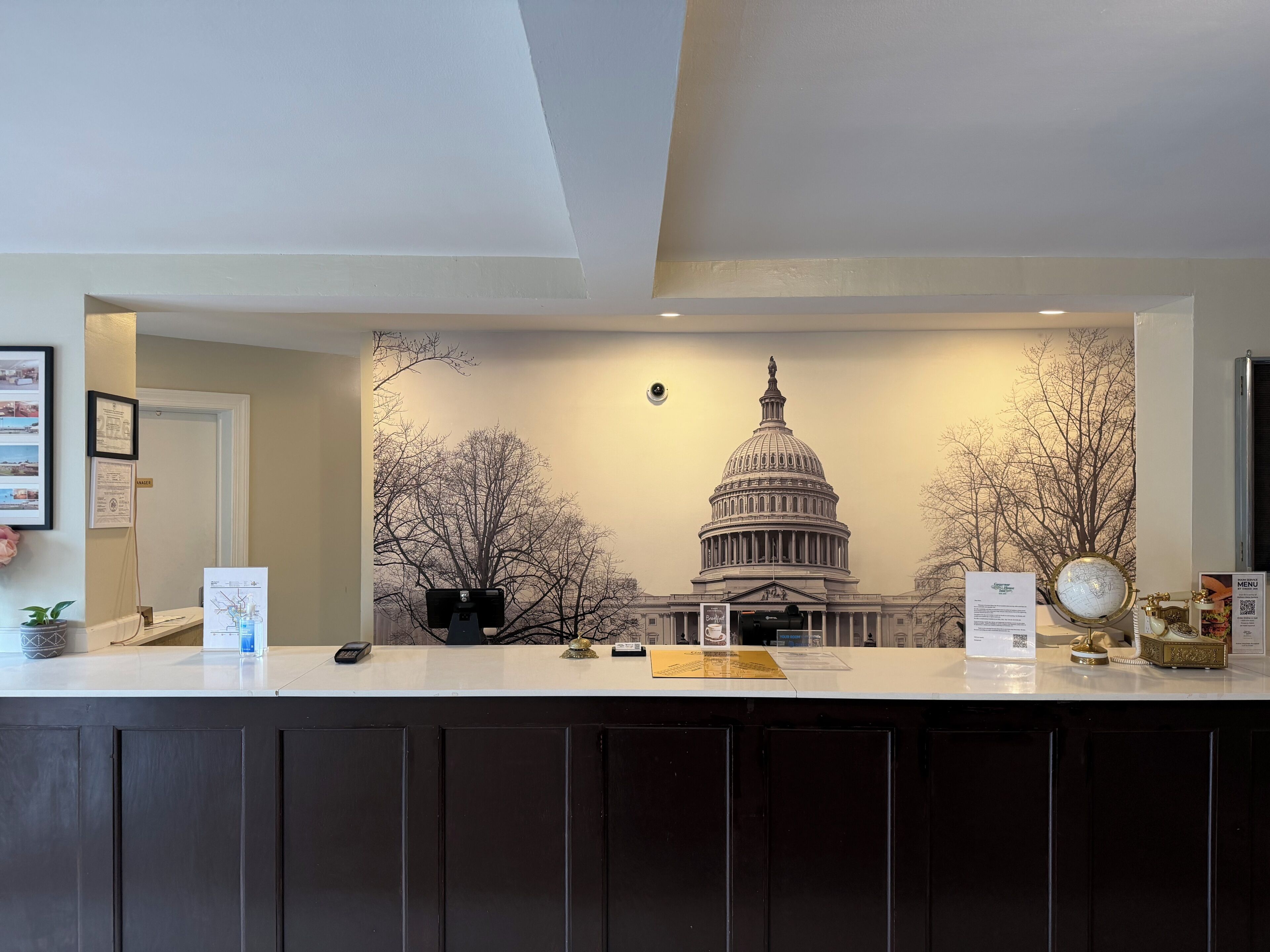 A reception desk with a backdrop of the U.S. Capitol building, a framed certificate on the wall, and a globe on the counter.
