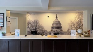 Un mostrador de recepción con el edificio del Capitolio de los Estados Unidos como fondo, un diploma enmarcado en la pared y un globo en la encimera.