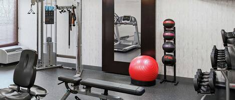 A gym with exercise equipment, a treadmill, and a mirror.