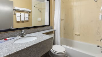 A bathroom with a granite sink, a mirror, a toilet, and a bathtub.
