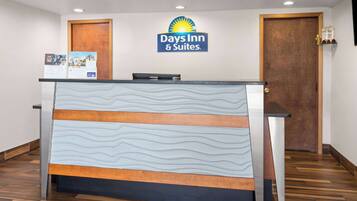 A reception desk with a Days Inn & Suites logo, a wooden door, and a bulletin board with information.