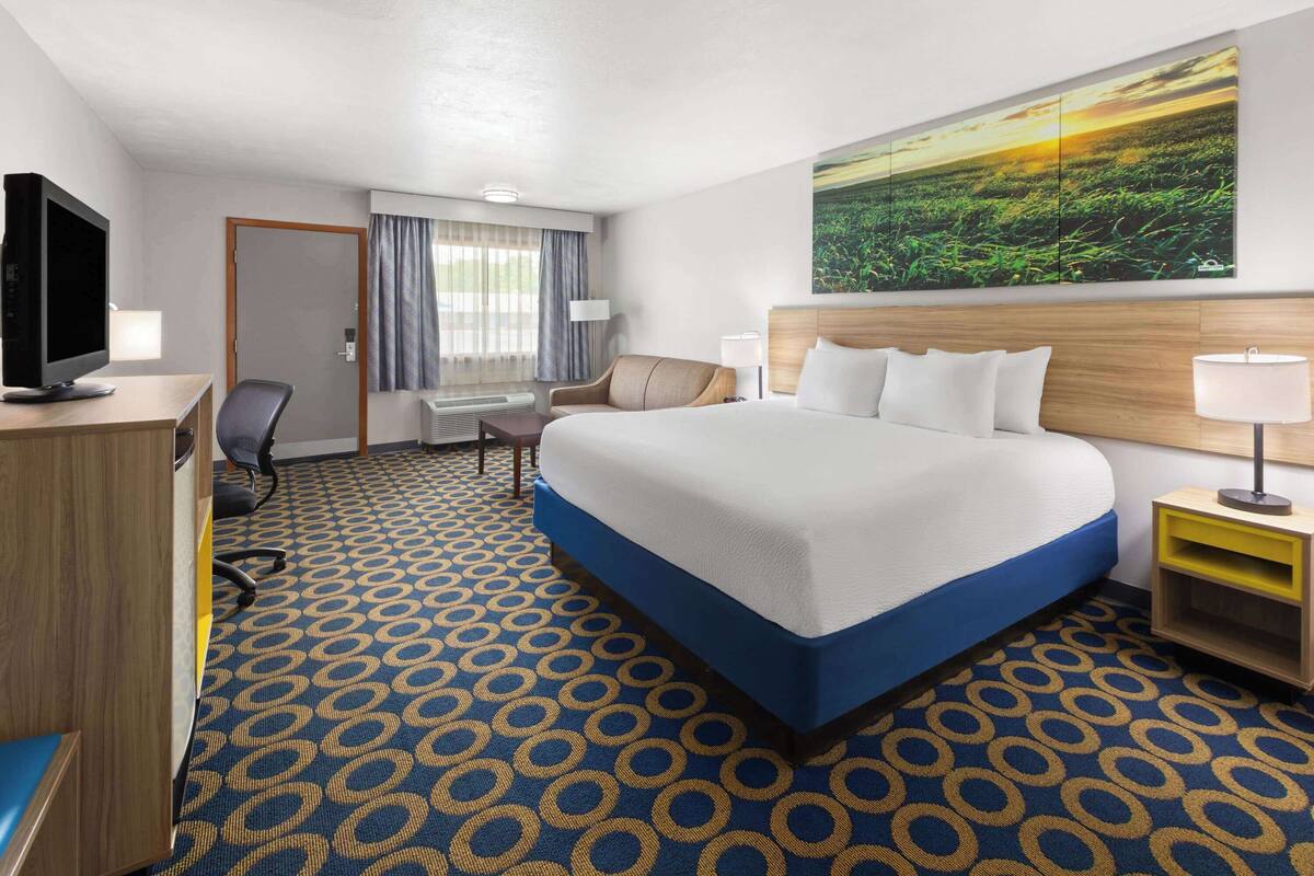 A hotel room with a large bed, a desk with a computer, a chair, and a television.