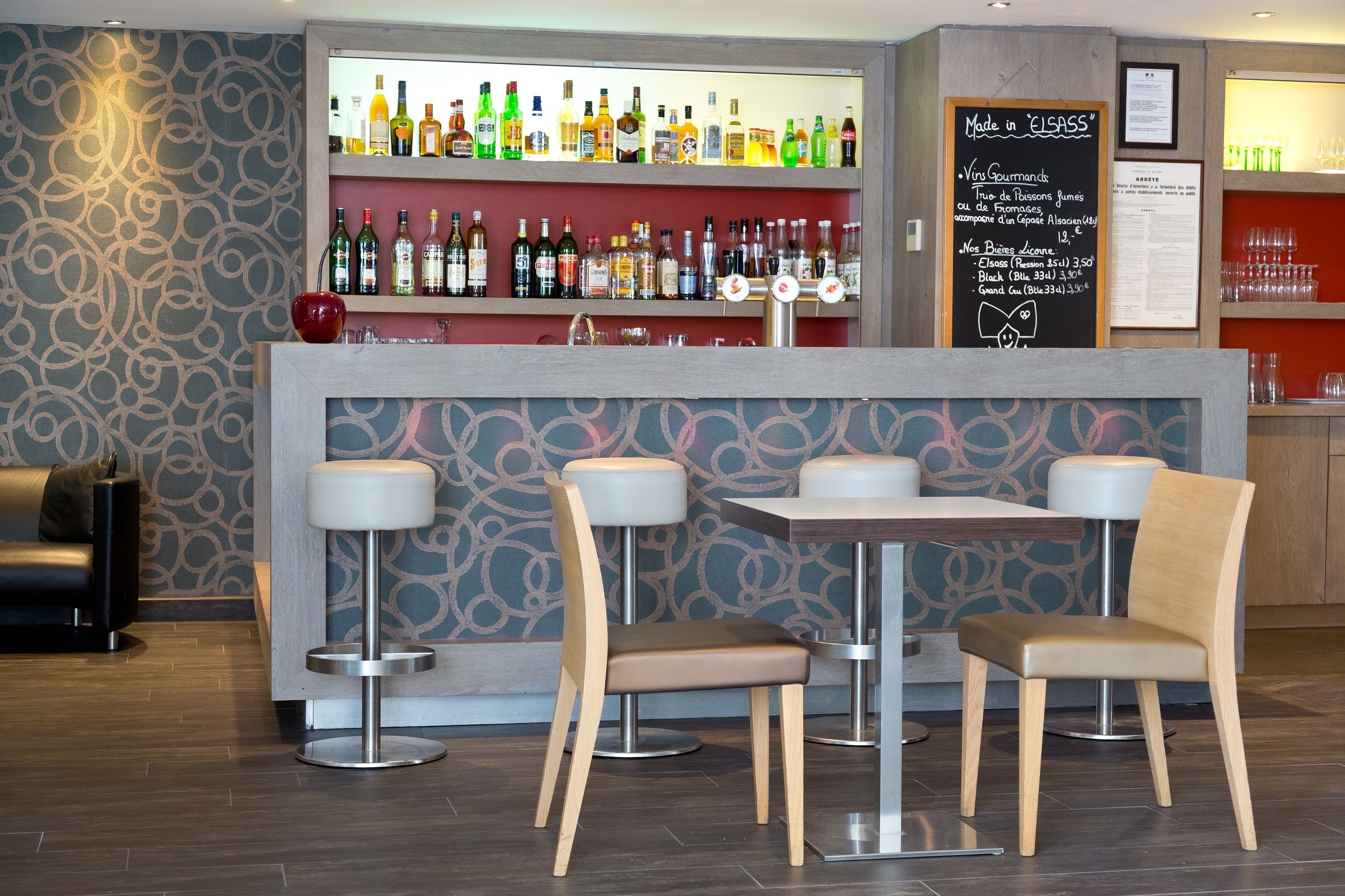 A bar area with a variety of liquor bottles, two bar stools, and a table with chairs.