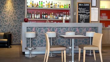 A bar area with a variety of liquor bottles, two bar stools, and a table with chairs.