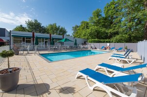 Una piscina al aire libre de temporada, sillones reclinables de piscina