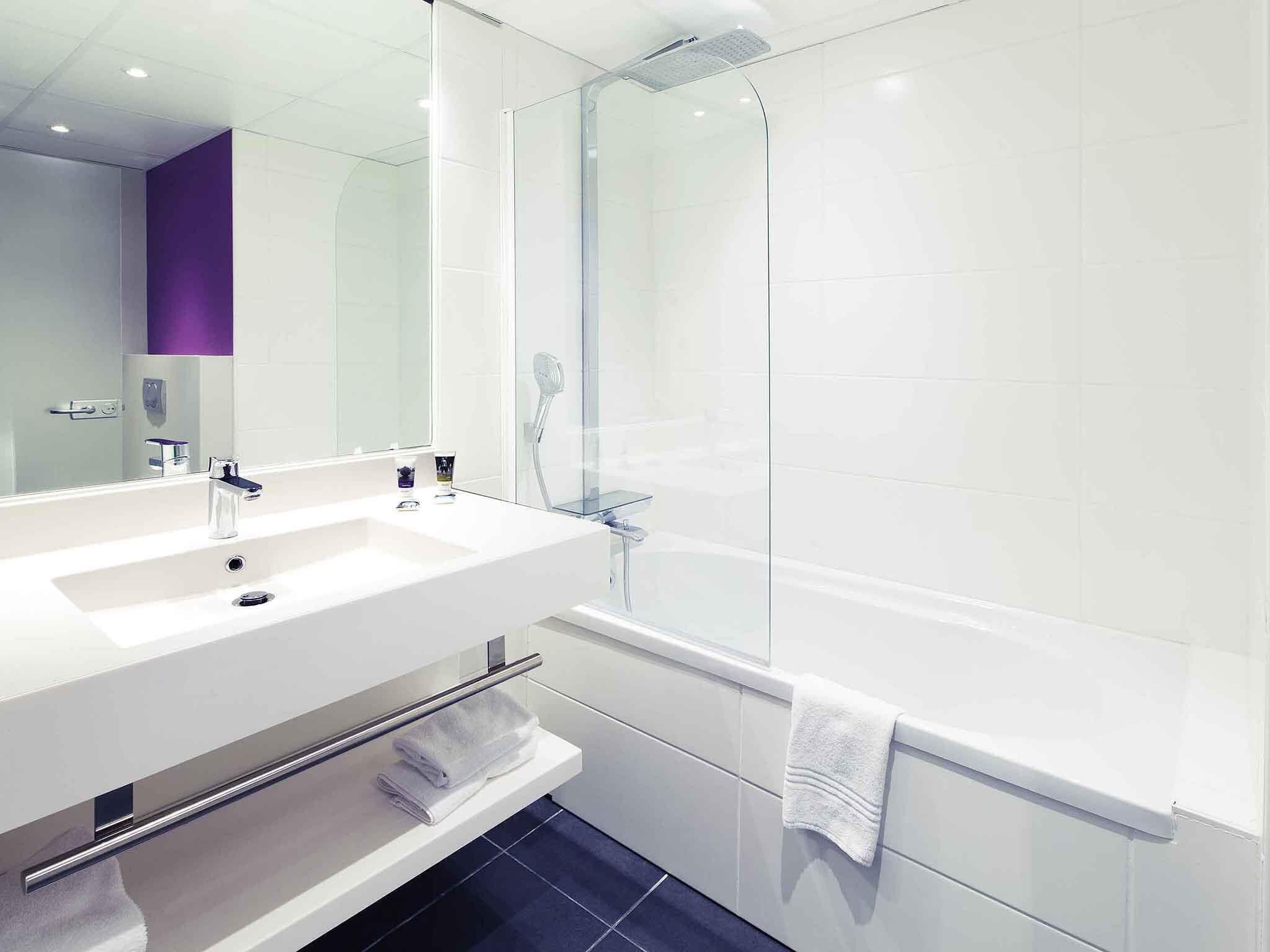 A modern bathroom with a white sink, a glass shower enclosure, and a large mirror.