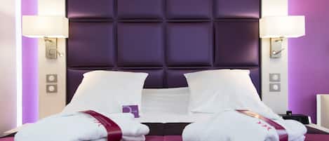 A hotel room with a large bed, two bedside lamps, and a headboard with a padded design.