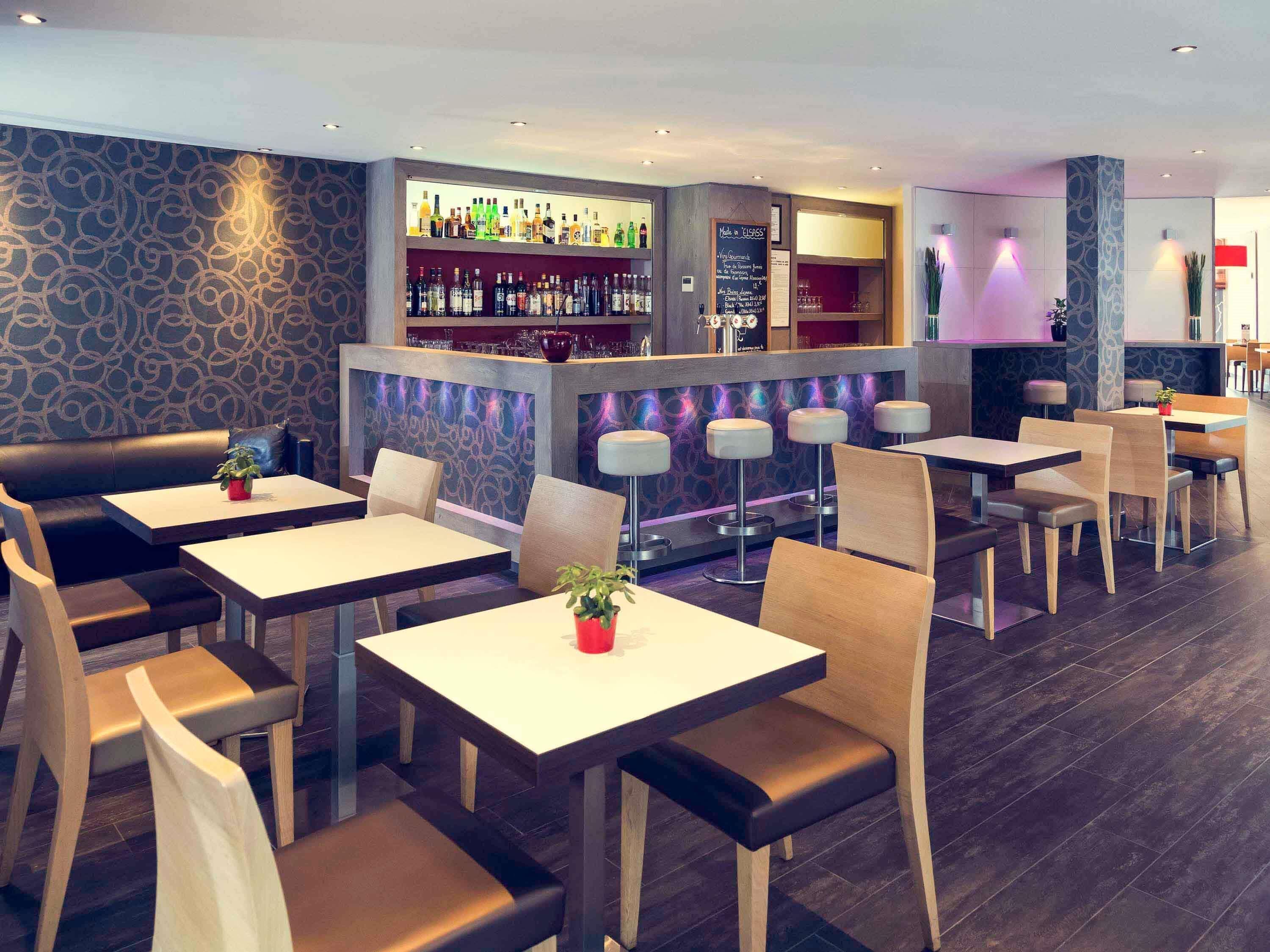 A restaurant with bar seating, tables, and a patterned wall.